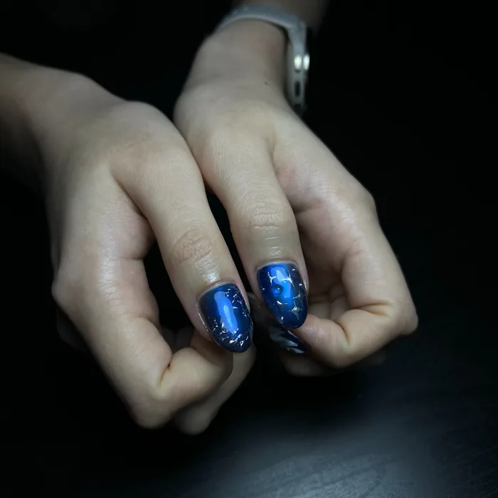 A deep blue chrome set catching the light across all five nails